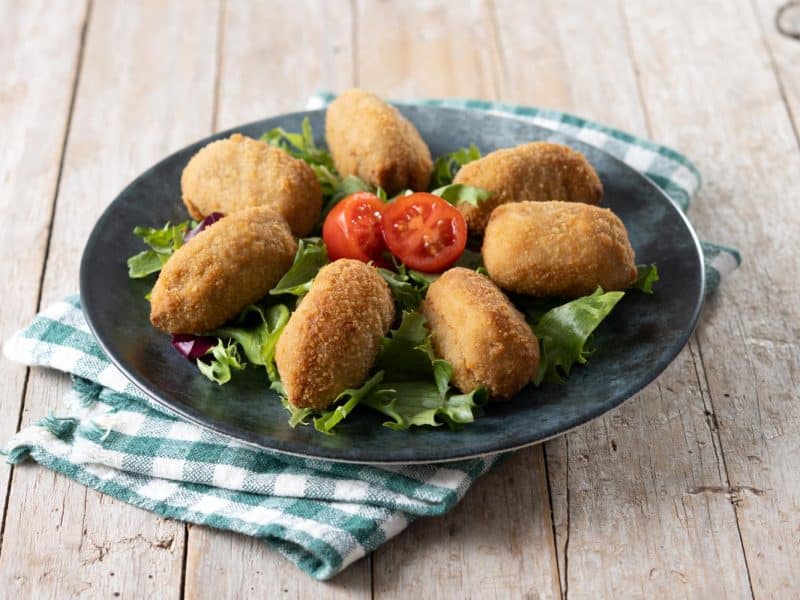 Prato servindo bolinho de bacalhau com salada como opção para o almoço de Páscoa